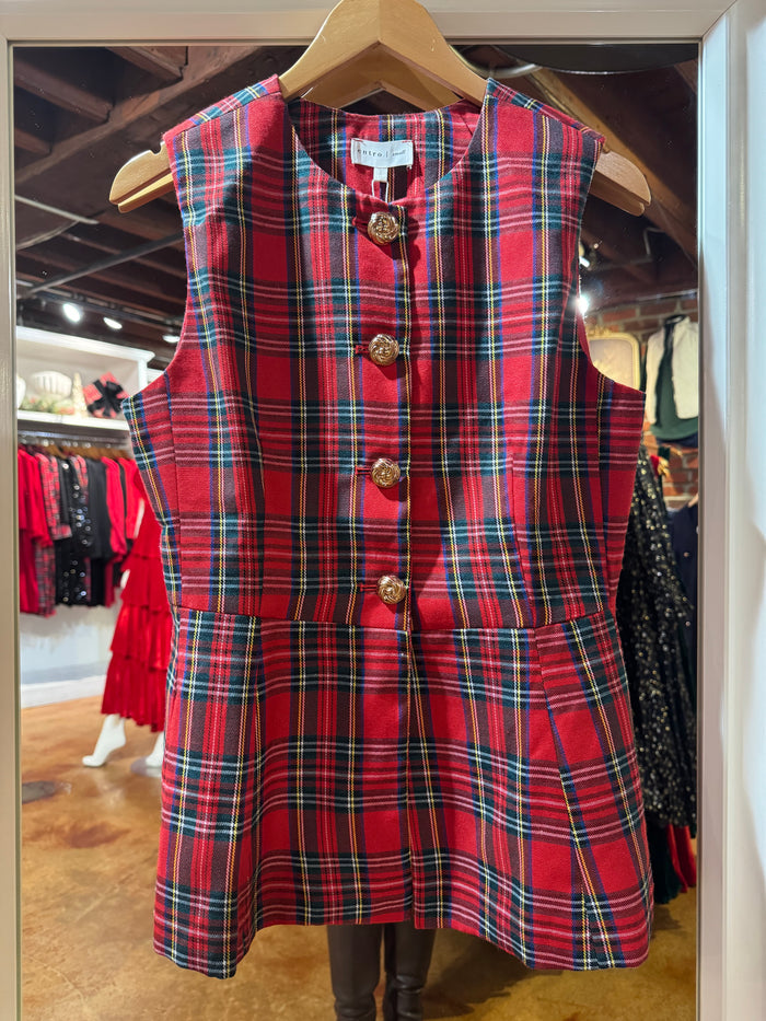 Red plaid sleeveless top with gold buttons on a hanger in a store setting