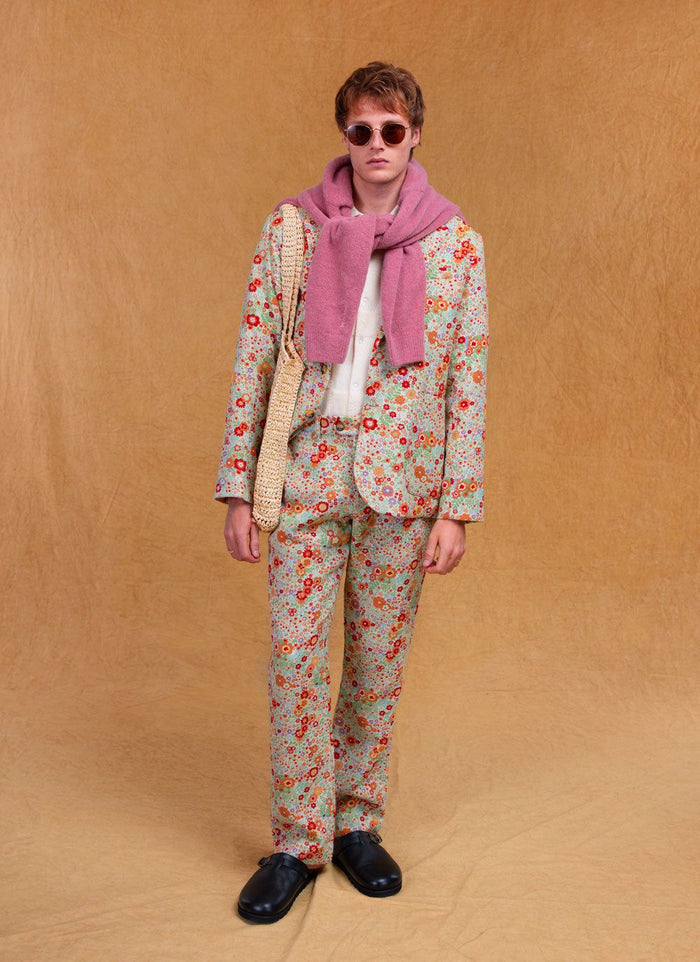 A model wears the Percival floral tailored blazer and matching trousers, styled with a pink jumper and sunglasses.