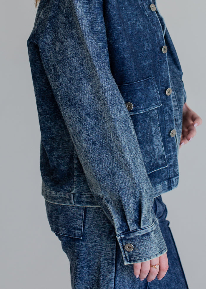 Person wearing a blue denim jacket on a gray background