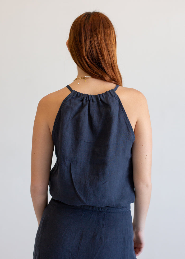 Woman wearing a navy blue sleeveless top and skirt set against a plain background