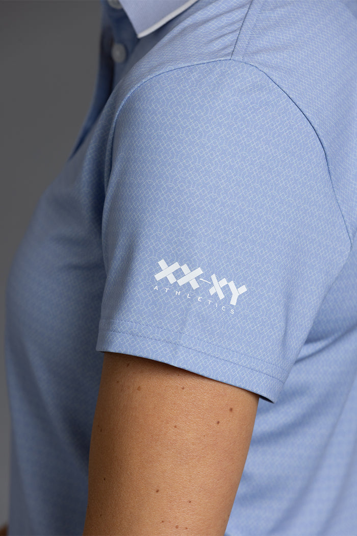Close-up of Lavender Graypolo shirt with a logo on the sleeve against a gray background || Lavender Gray