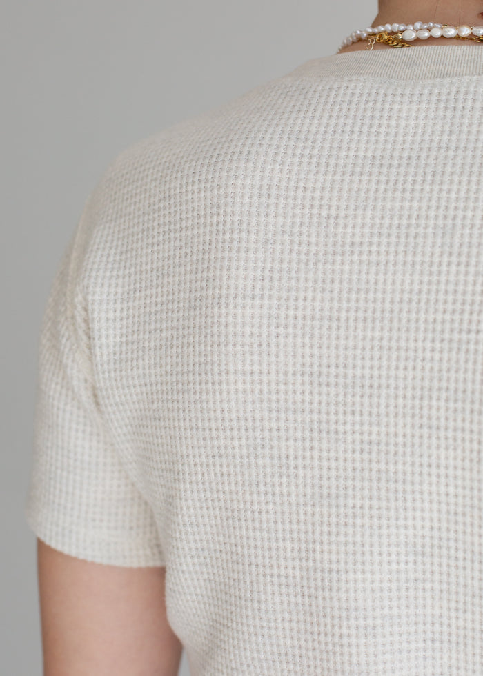 Close-up of a person wearing a textured beige shirt against a gray background