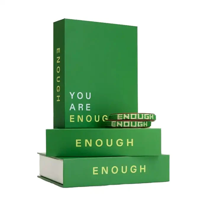 A green book-shaped box with the word 'ENOUGH' printed on the cover, displayed stacked on top of two matching green boxes.