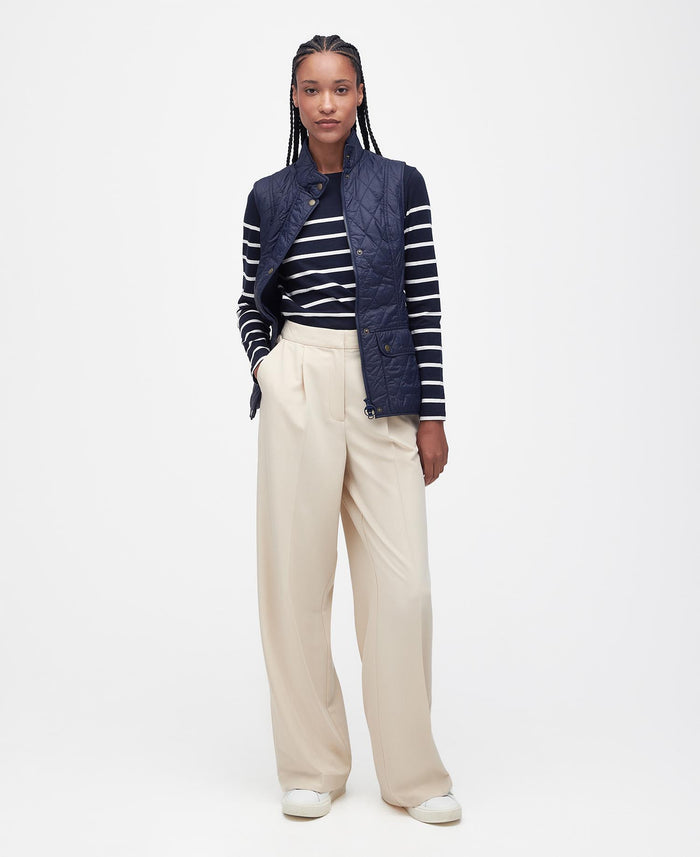 Person wearing a navy jacket, striped shirt, and beige pants on a white background