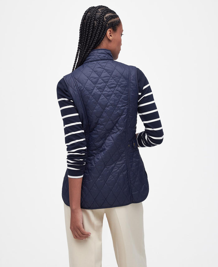 Person wearing a navy quilted vest on a white background