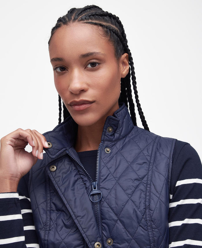 Woman wearing a navy quilted jacket with a white background