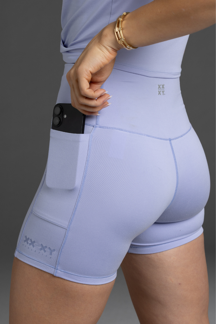 Lavender athletic shorts with a brand logo on a gray background || Lavender Gray