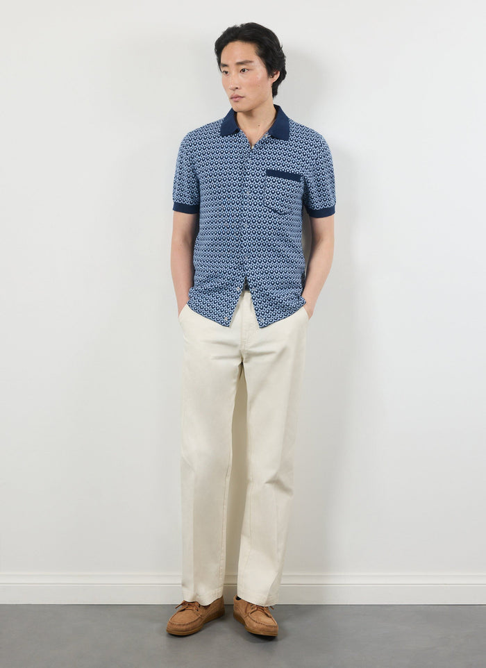 A model wears the Percival Casa Piccante blue jacquard knitted shirt with cream trousers and brown suede loafers.
