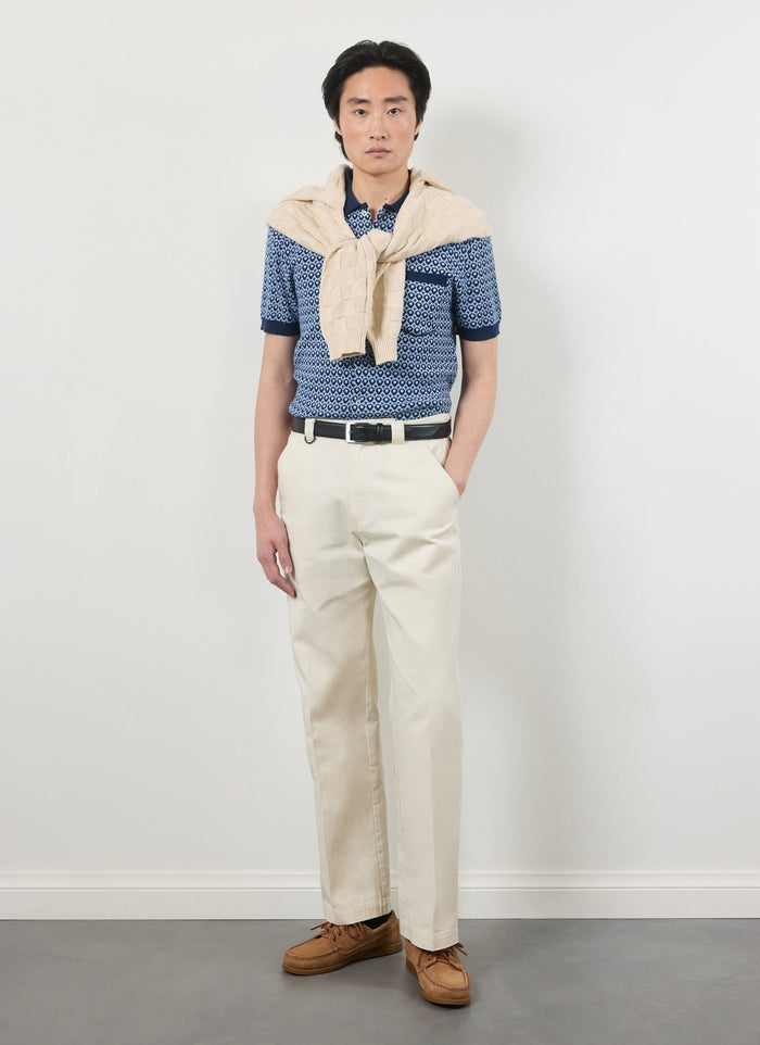 Model wears the Percival Casa Piccante Shirt in Blue Jacquard with cream trousers and a jumper over his shoulders.