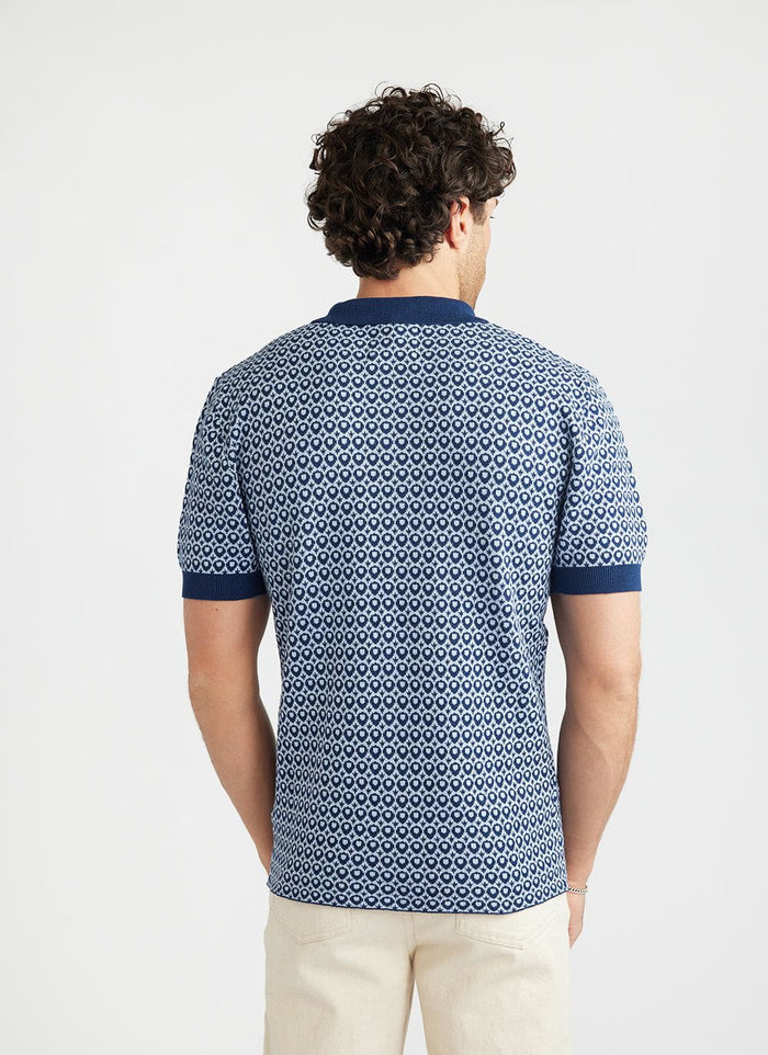 Rear view of a model wearing the Percival Casa Piccante shirt, a blue jacquard knitted top with short sleeves.