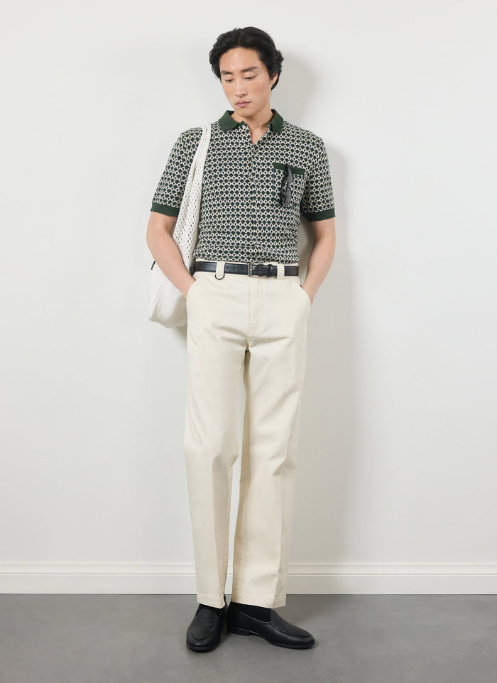 A model wears the Percival Casa Piccante green jacquard knitted shirt with cream trousers and black loafers.