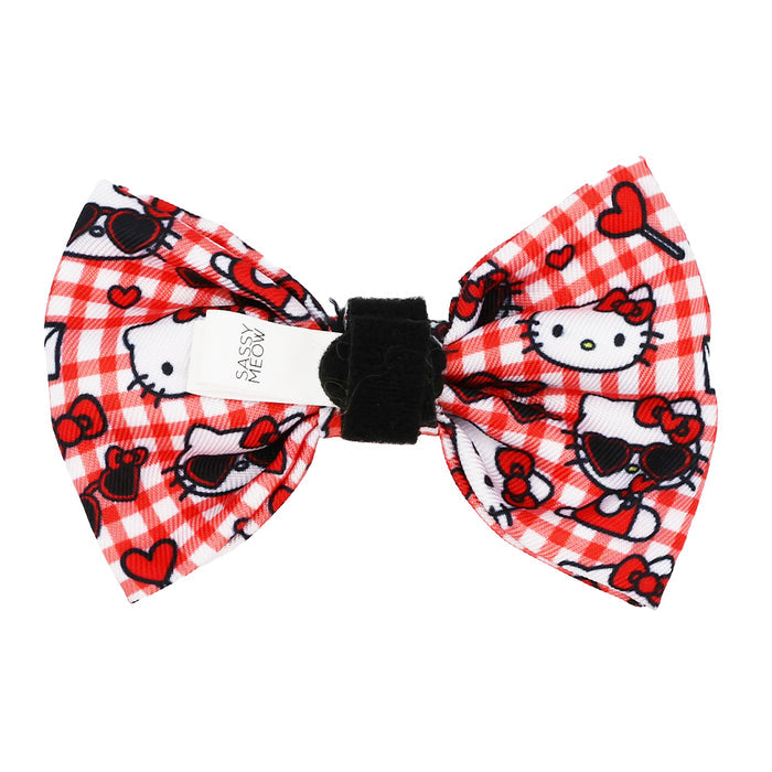 The Cat Bowtie - Hello Kitty® Red Classic by Sassy Woof features a red and white checkered pattern with Hello Kitty and red bow designs, a black center, a white Sassy tag, plus black heart sunglasses and red hearts.