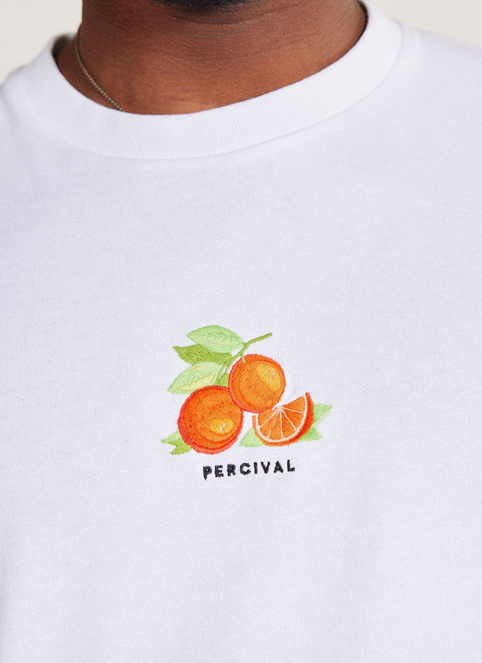 Close up of the embroidered orange citrus graphic on the white Percival t-shirt