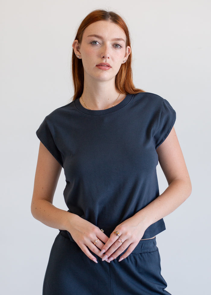 Woman wearing a navy blue top and pants against a plain background