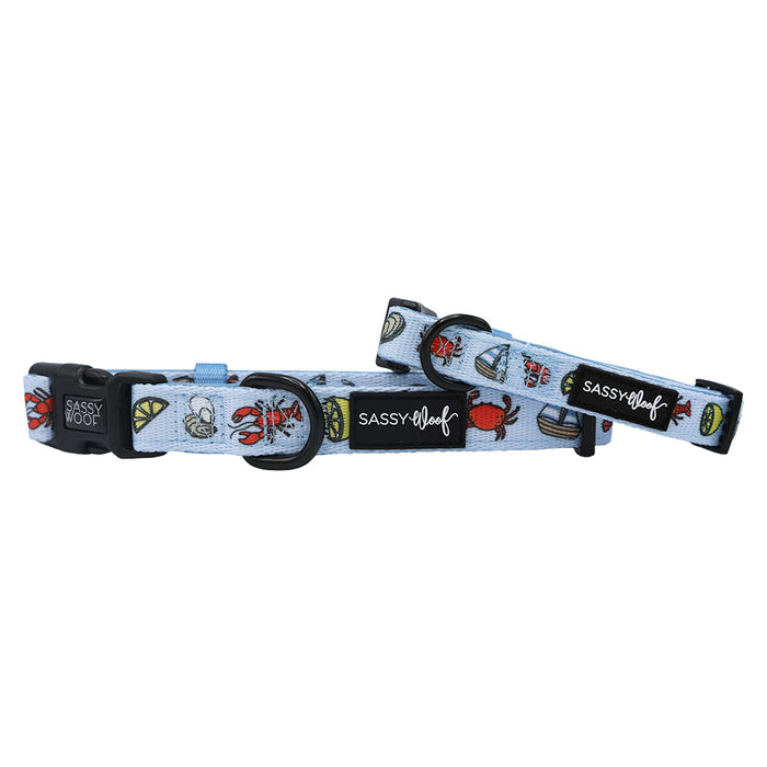 The Sassy Woof "Dog Collar - Coastal Cuties" features light blue collars with playful nautical and beach-themed designs—crabs, boats, and lime wedges—making them the perfect coastal accessory for your pup’s next adventure.