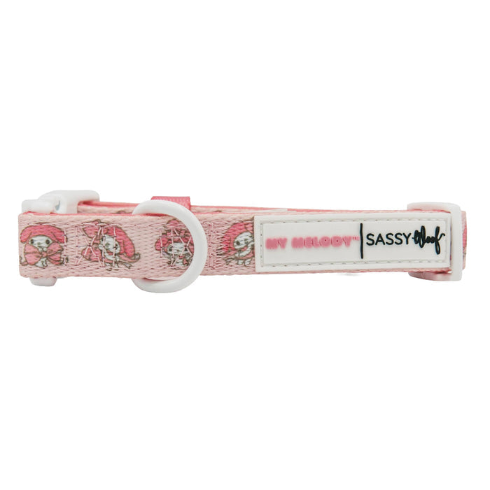 The Sassy Woof Dog Collar - My Melody™ is a pink adjustable collar featuring My Melody characters, a white plastic buckle, metal ring, and a label with MY MELODY™ and Sassy Woof—a must-have for Hello Kitty and My Melody fans.