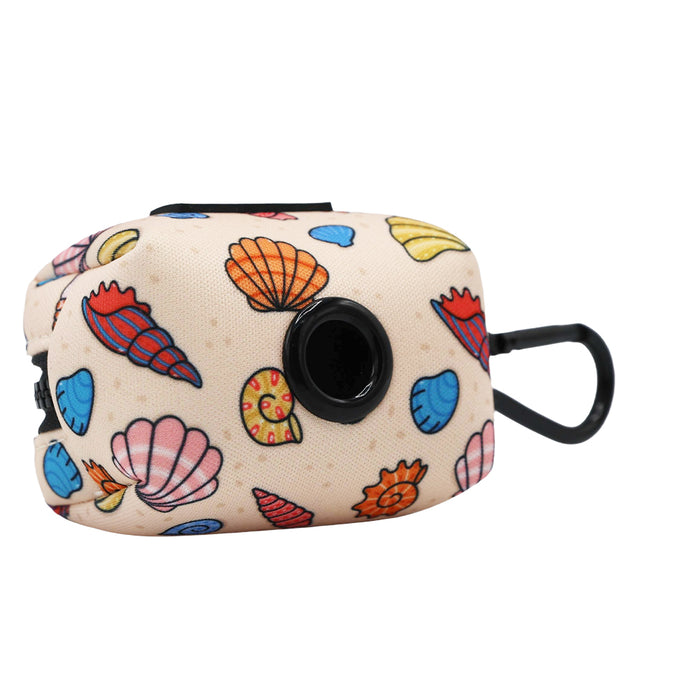 The "Shell Yeah" Dog Waste Bag Holder by Sassy Woof is a beige accessory with colorful seashell prints, featuring a black dispenser and clip—ideal for adding beachy style to your dog's leash.