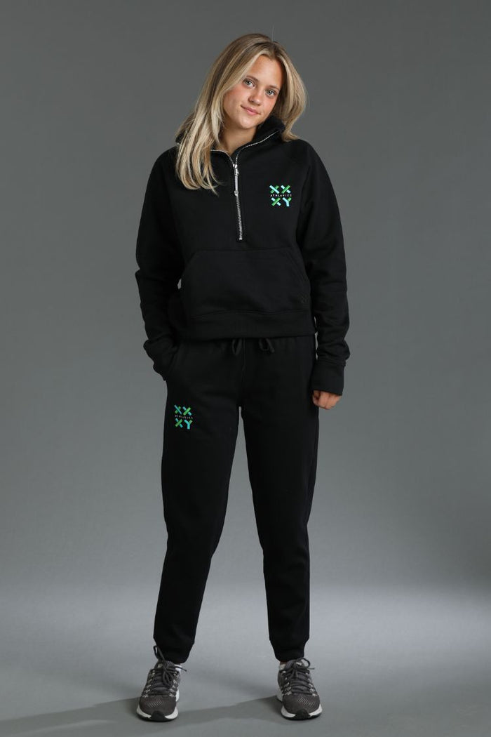 Person wearing a black tracksuit with green logos on a gray background || Black