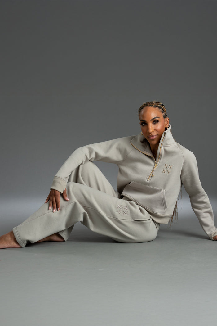 Person wearing a Light gray tracksuit sitting on a gray background || taupe
