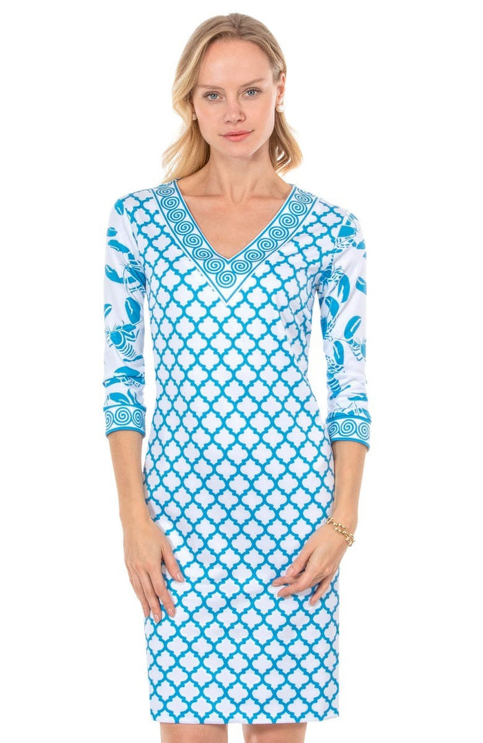 Blonde woman wearing turquoise and white geometric print 3/4 sleeve v-neck dress with contrast lobster print on sleeves