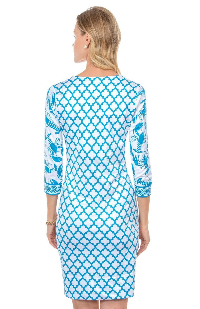 Blonde woman facing away wearing turquoise and white geometric print 3/4 sleeve dress with contrast lobster print on sleeves