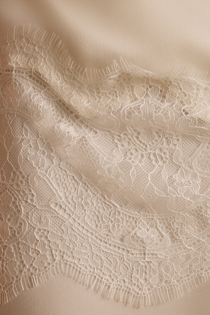 Close-up of floral lace trim edging the cream satin Halo pants.