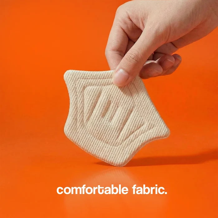 Heel cushion pad held by a hand, featuring a textured beige fabric against an orange background.