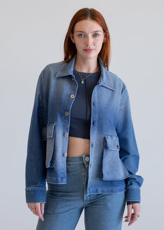 Woman wearing a blue denim jacket and jeans against a plain background