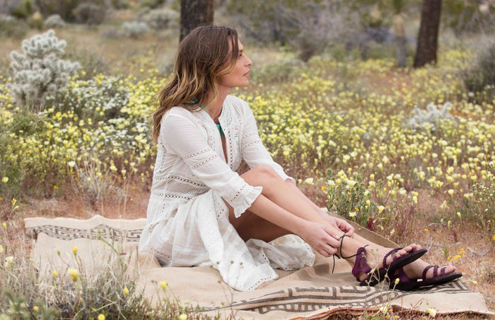 a female model sitting on blanket wearing Jerusalem sandals