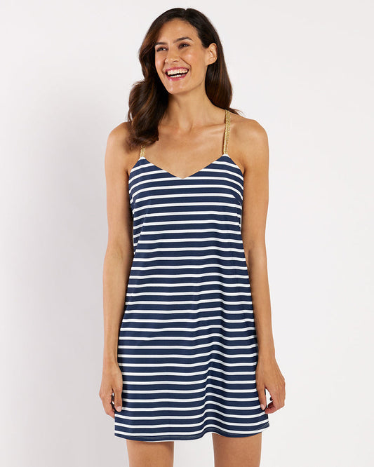 Smiling model in a navy and white mini dress with gold straps