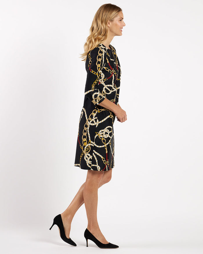 Woman wearing a black dress with gold chain pattern on a white background