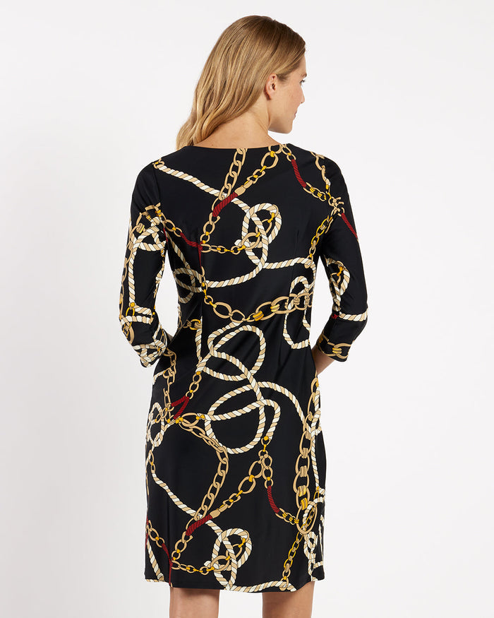 Woman wearing a black dress with gold chain pattern on a white background