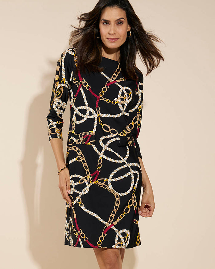 Woman wearing a black dress with gold chain pattern on a light background