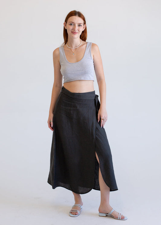 Woman wearing a gray crop top and black skirt on a white background