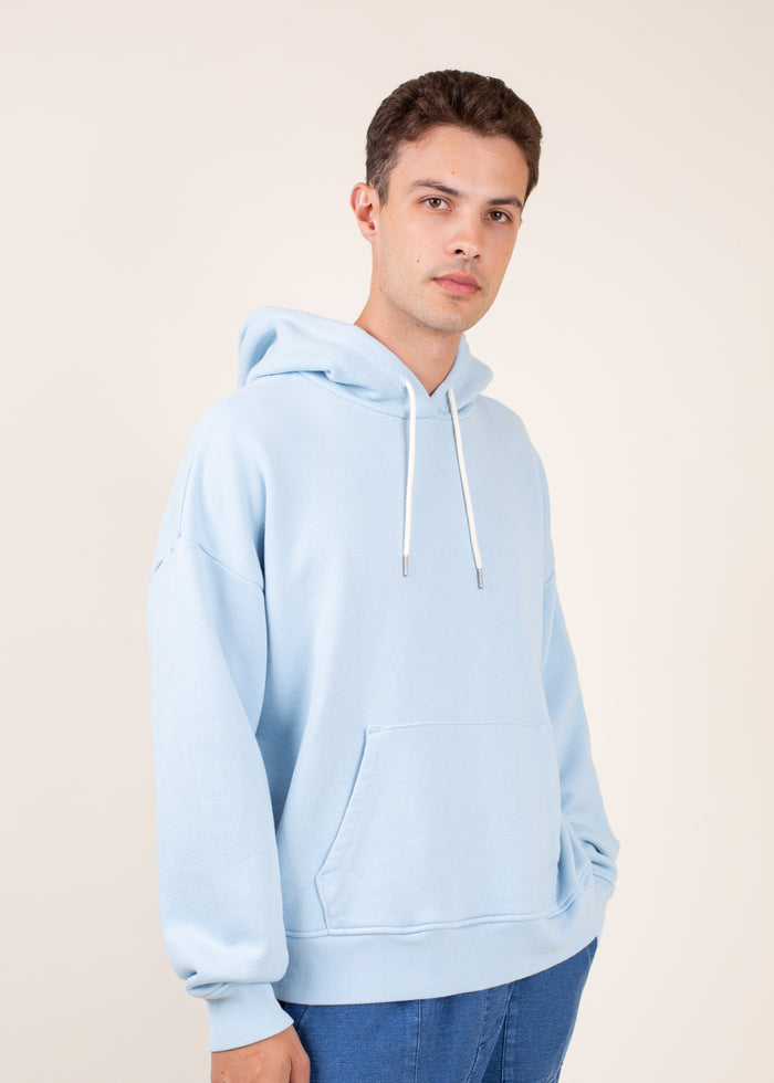Man wearing a light blue hoodie against a beige background
