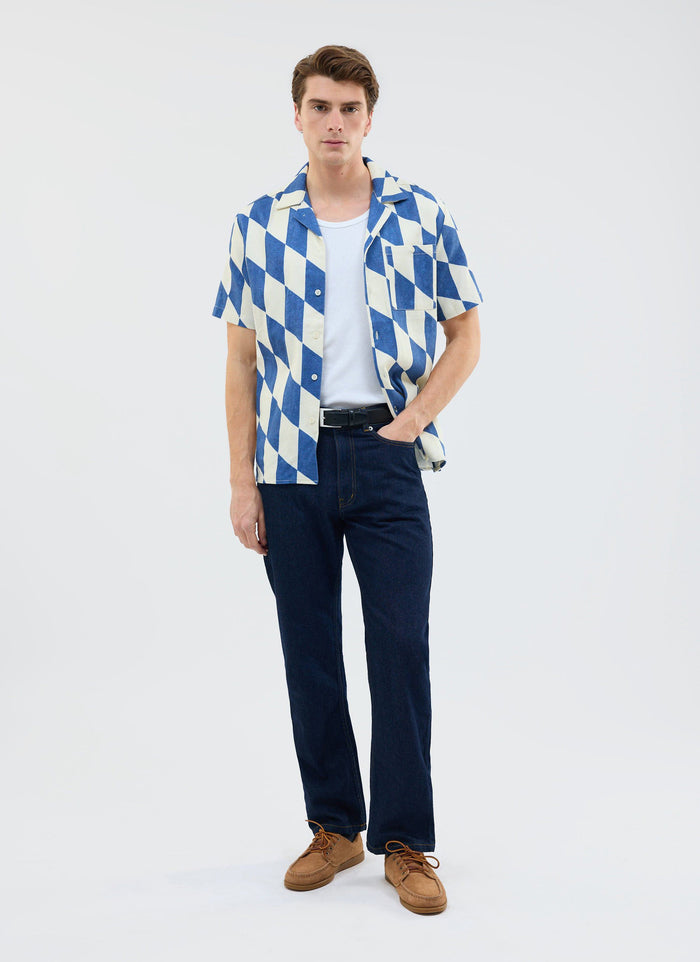 A model wears the Percival Market Diamond Cuban Shirt in ecru and navy, styled with dark jeans and a white t-shirt.