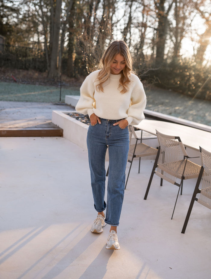 Woman wearing medium-blue straight jeans with cream sweater