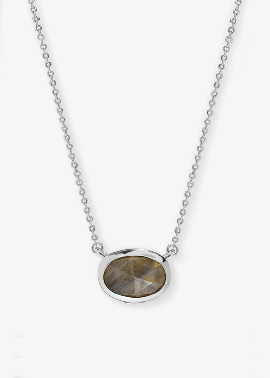 Silver necklace with a silver framed oval labradorite pendant laying on a grey background