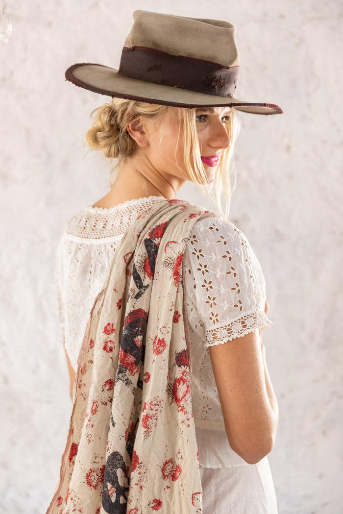 Woman in Magnolia Pearl artisan hat and floral skull scarf, vintage lace blouse, whimsical style