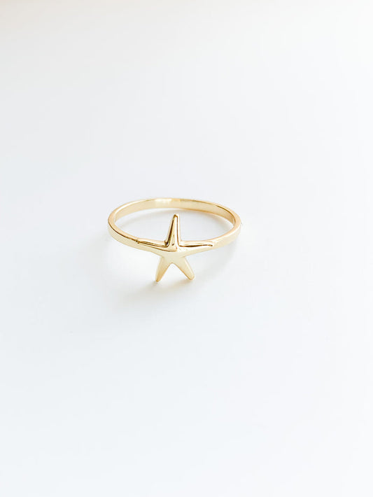 A gold-colored ring featuring a starfish design against a white background.