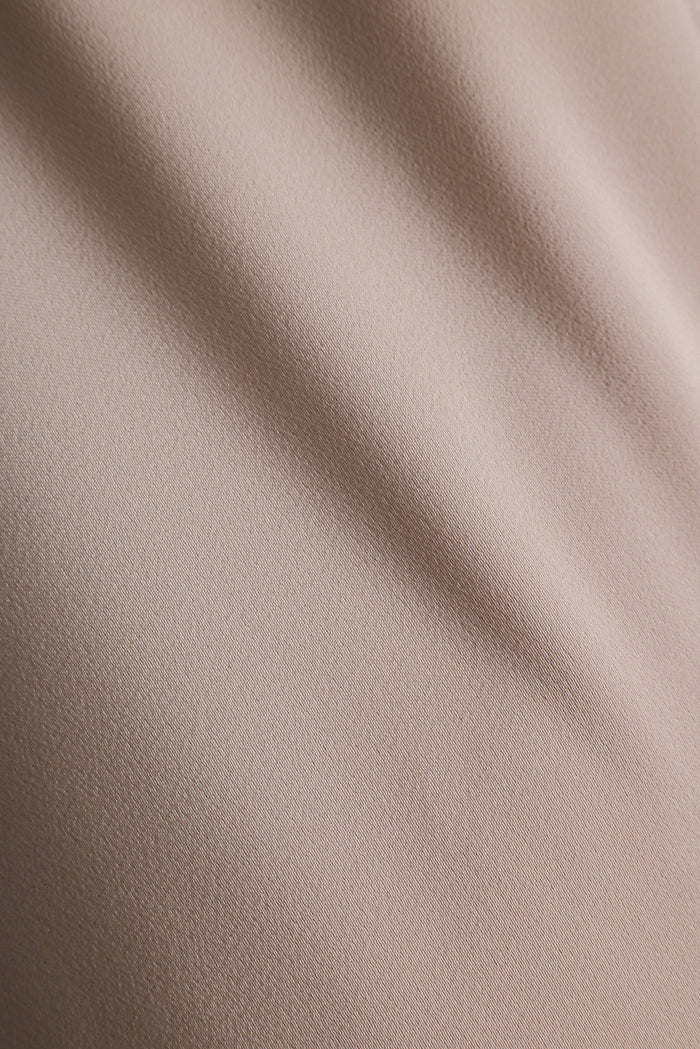 Close up of taupe satin fabric with soft, flowing folds.
