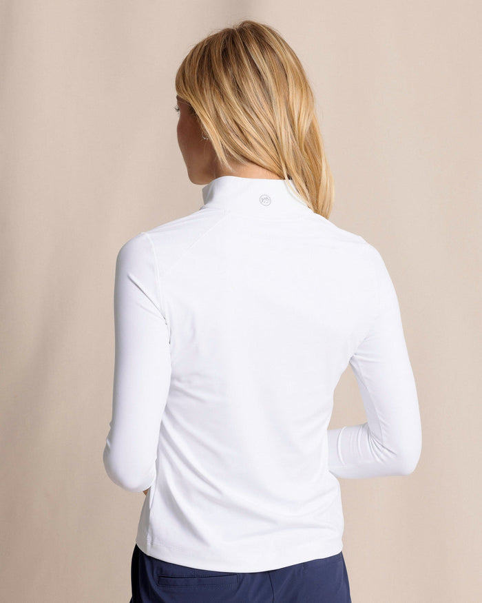 Woman wearing a white long-sleeve shirt with a high collar and 1/4 zip against a beige background