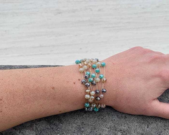 Stella beaded bracelet- aqua and pink. multiple strands of scattered beads on model.