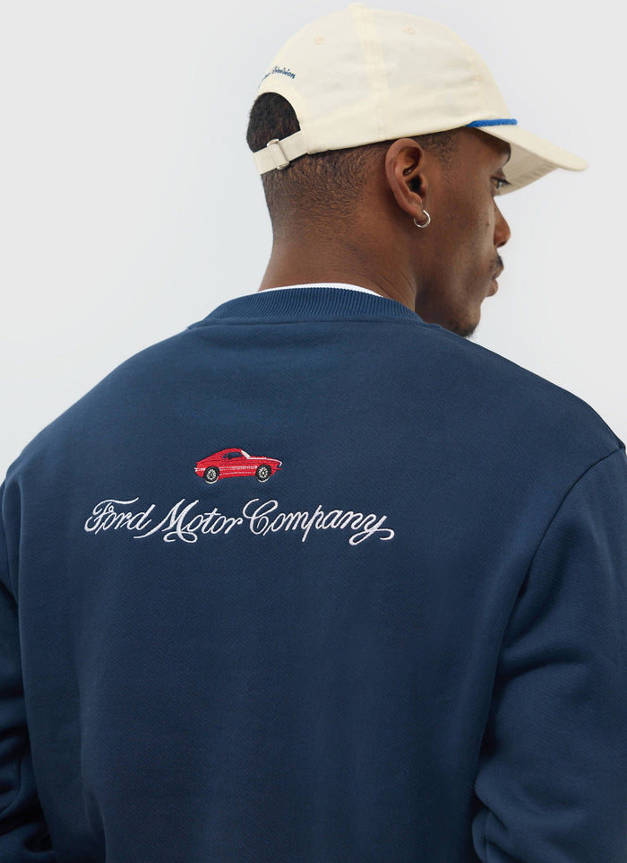 Close up on the back of a model wearing the navy Percival x Ford sweatshirt, showing the 'Ford Motor Company' embroidery.