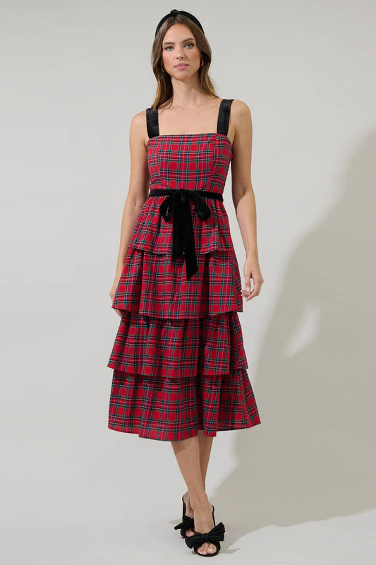 Woman wearing a red plaid dress with black straps and bow on a white background