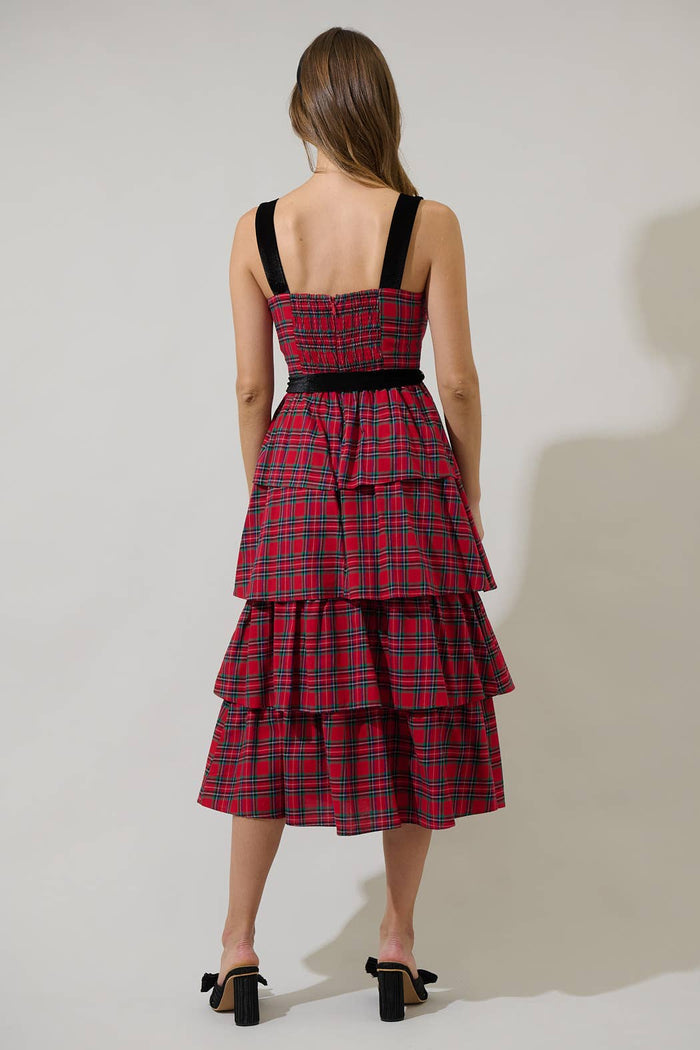 Woman wearing a red plaid dress with black straps on a plain background