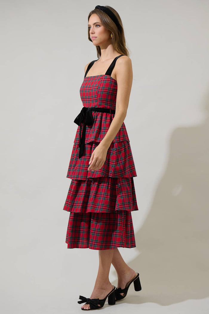 Woman wearing a red plaid dress with a black belt on a plain background