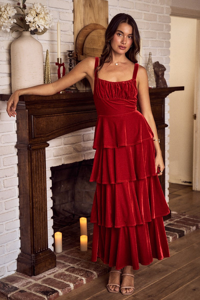 Woman in a red dress standing in a room with a fireplace.