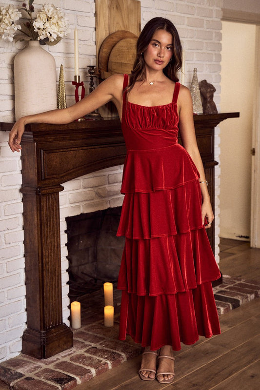 Woman in a red dress standing in a room with a fireplace.