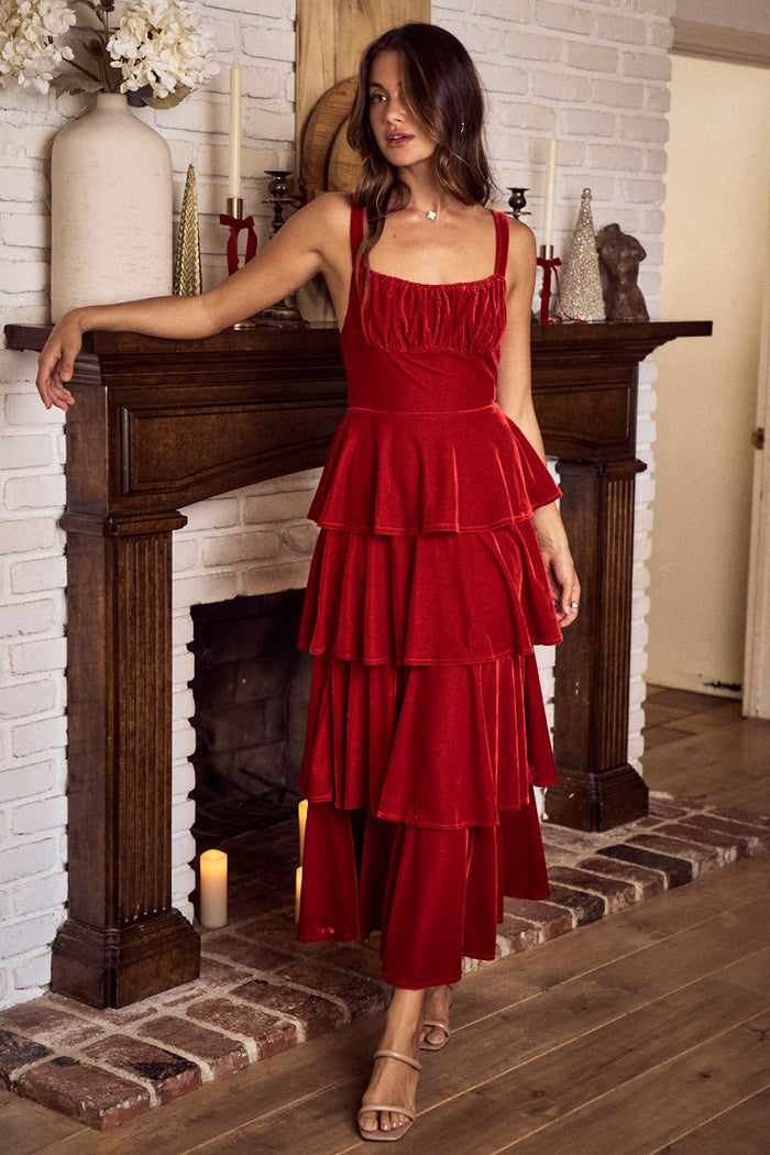 Woman in a red dress standing in front of a fireplace.